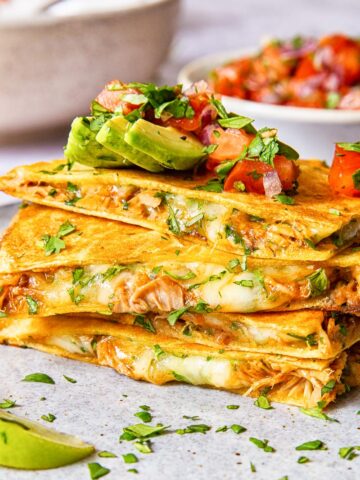 quesadilla pieces stacked on top of each other and topped with avocado and pico de gallo