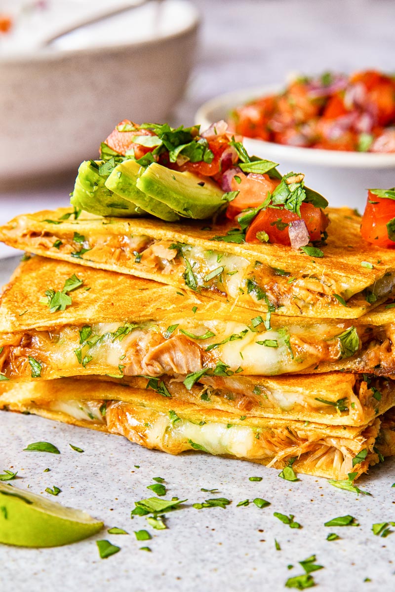 quesadilla pieces stacked on top of each other and topped with avocado and pico de gallo