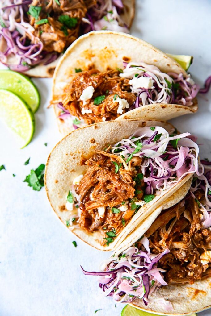 soft corn tacos filled with pulled pork and slaw