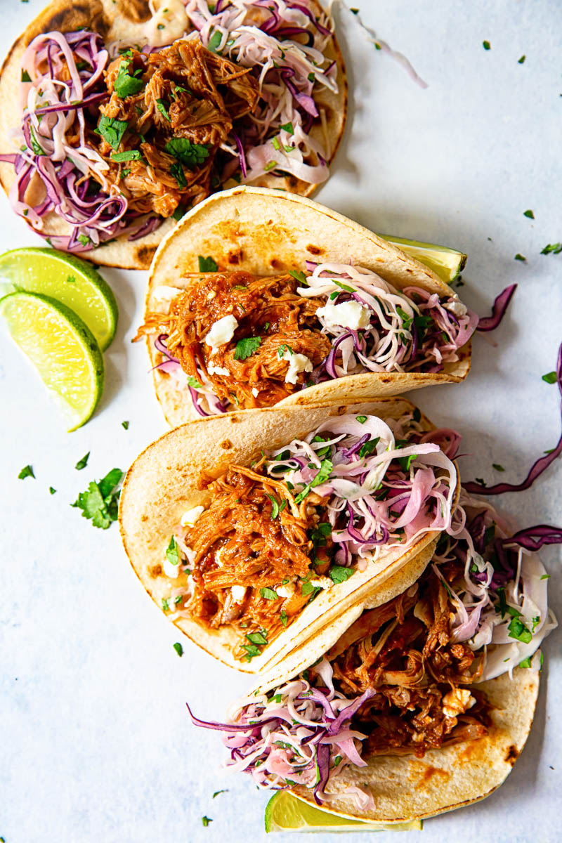 4 soft tacos filled with pulled pork and red and white slaw