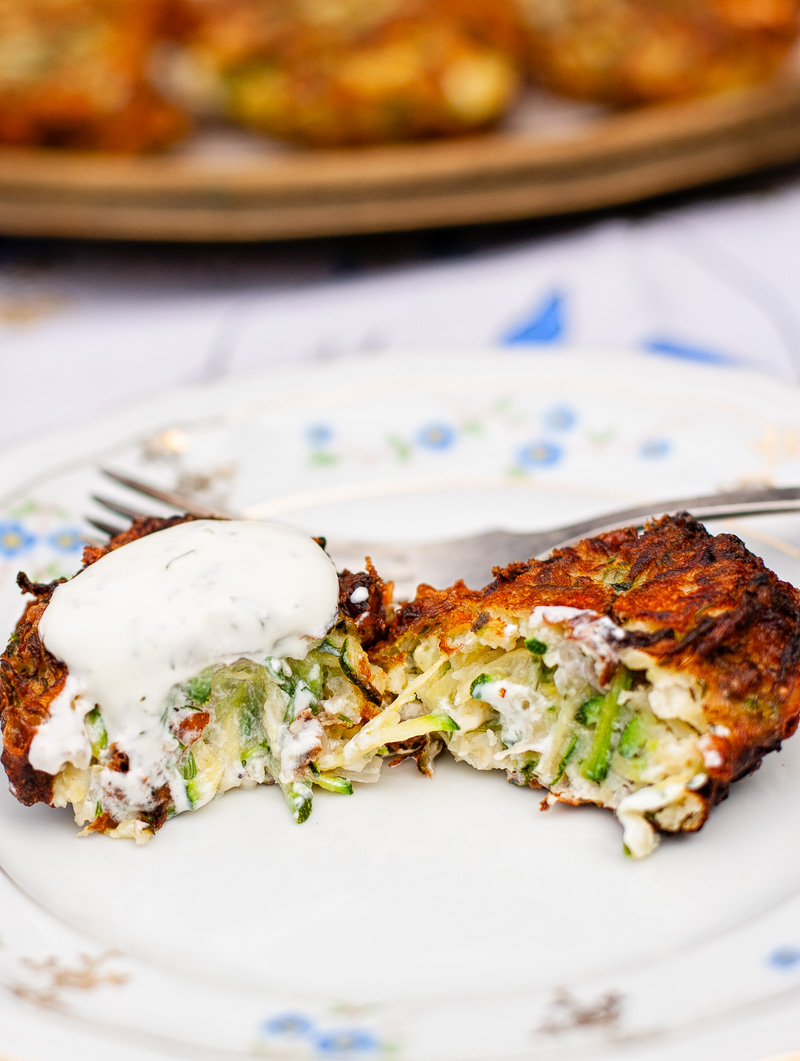 zucchini fritter cut in half and topped with yogurt sauce on a plate