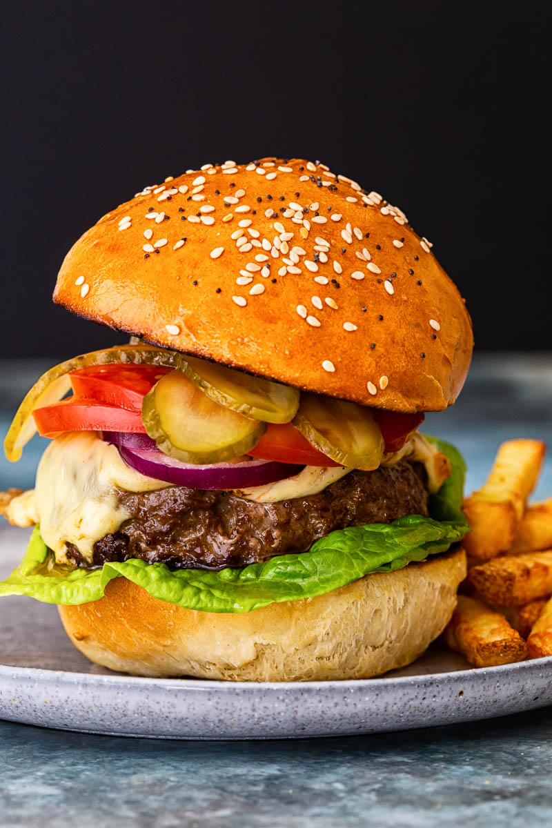 a cheeseburger with onion, tomatoes and pickles