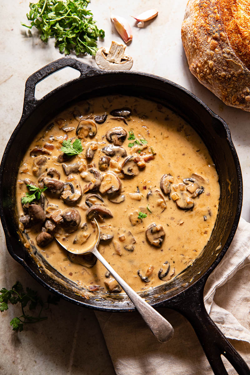 top down view of mushroom sauce in cast iron pan and a loaf of bread