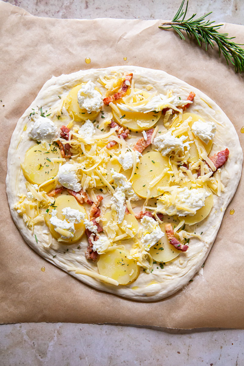 pizza dough topped with potatoes, pancetta and cheese, unbaked