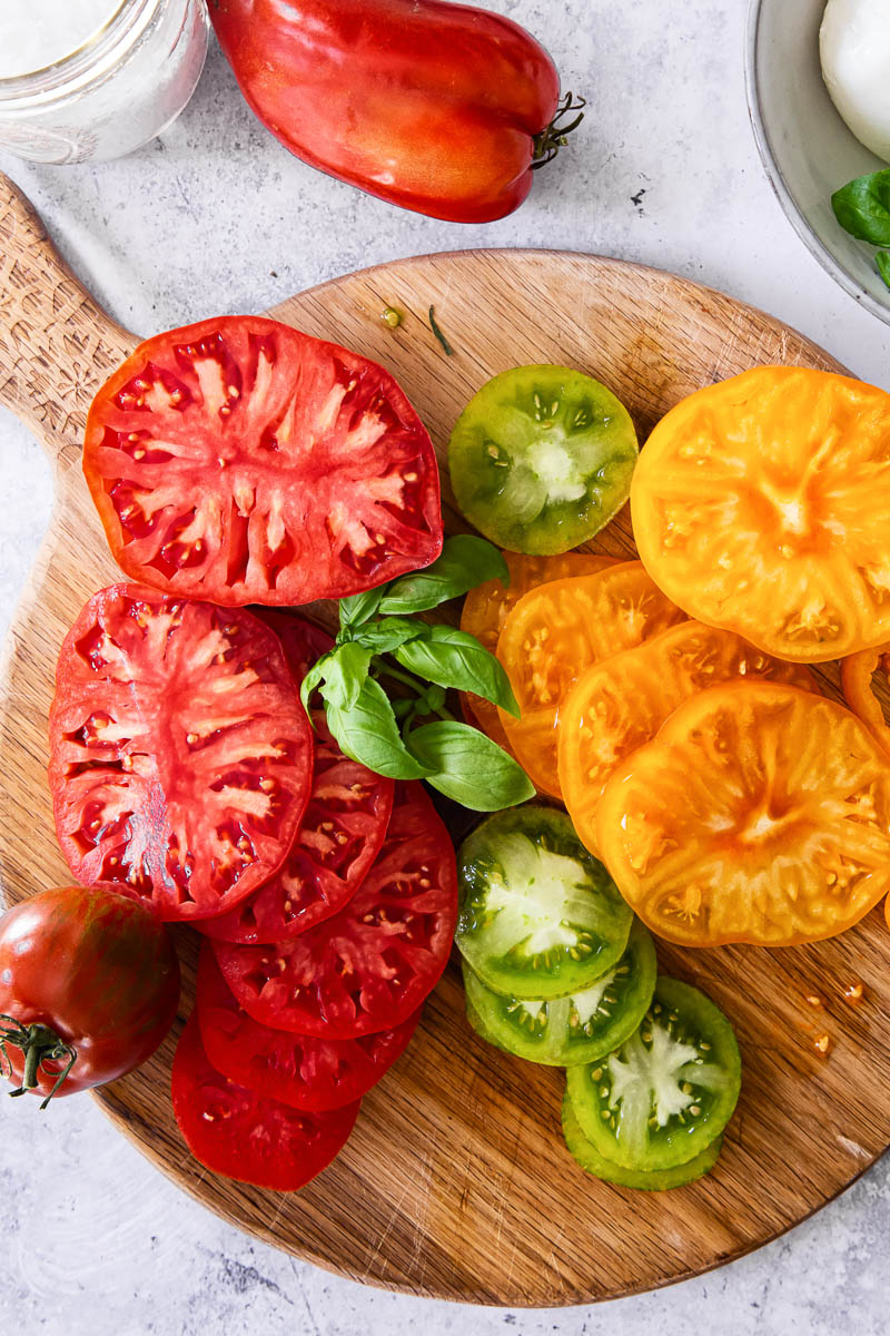 sliced heirloom tomatoes and basil on wooden board