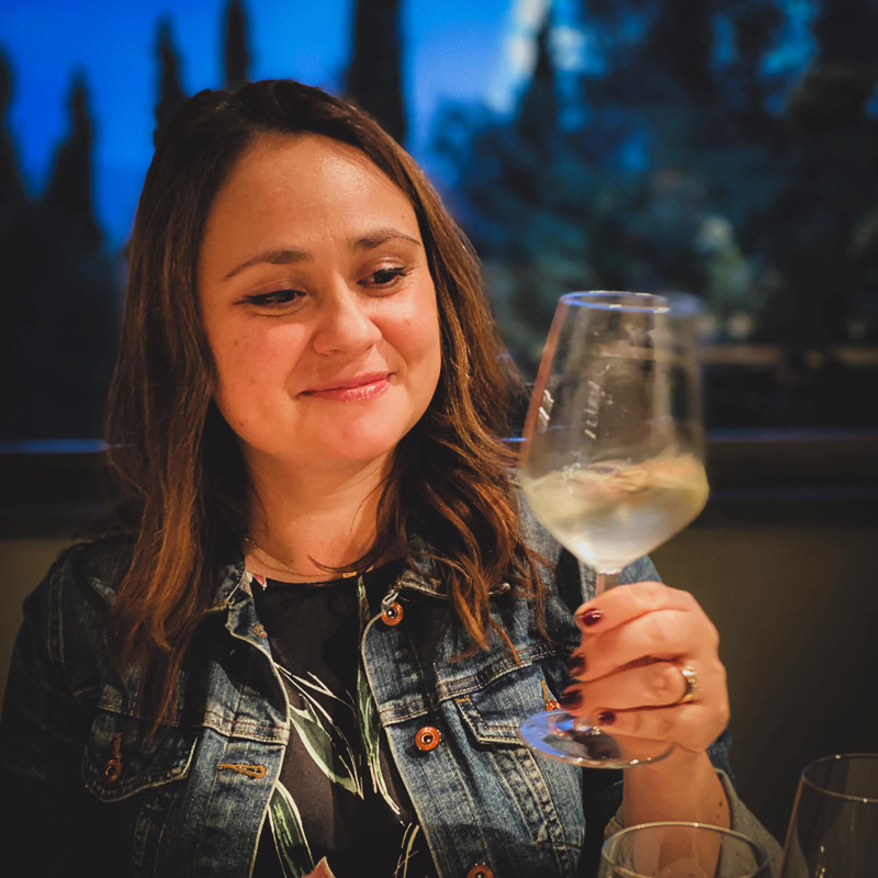 a woman holding a glass of white wine
