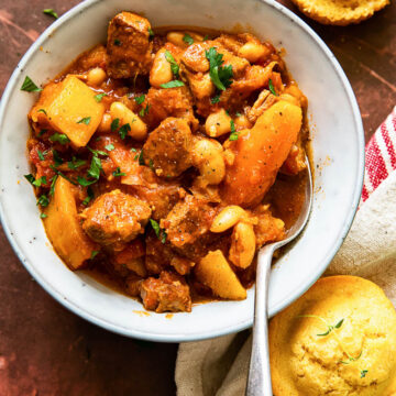 pork stew with carrots and butternut squash in bowl, cornbread muffins