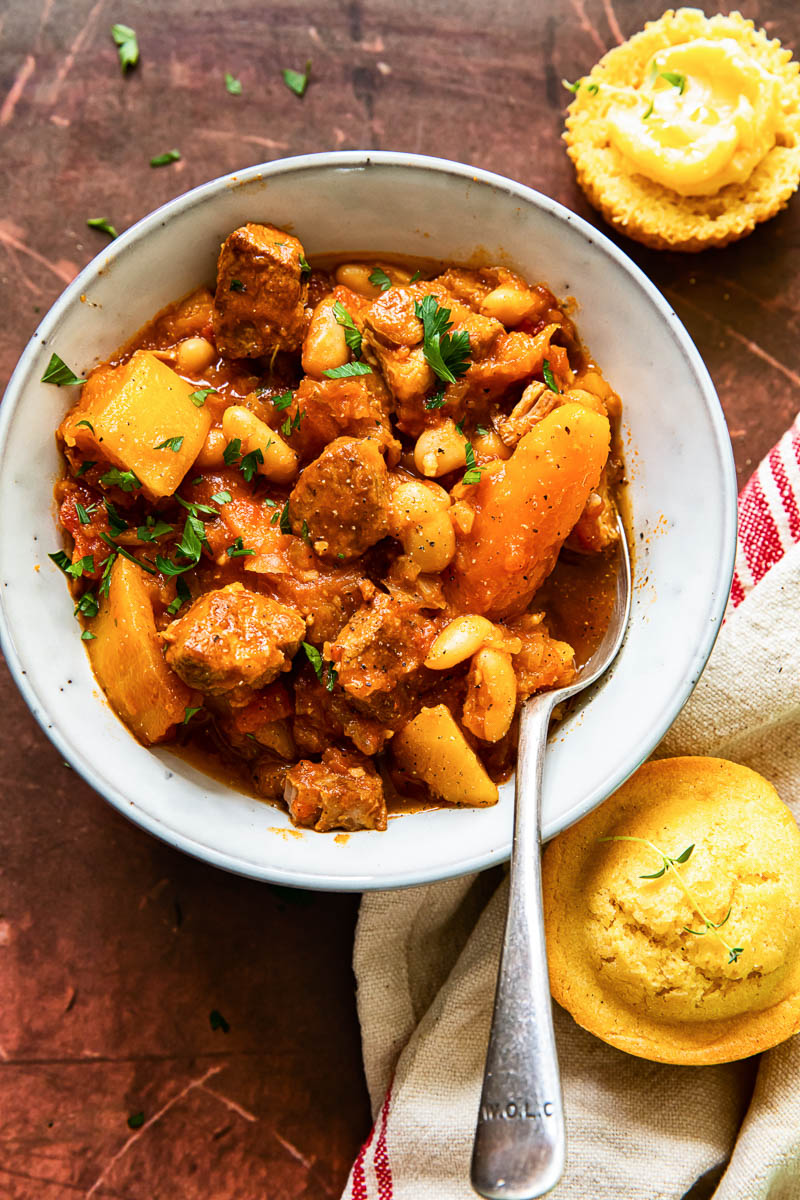 pork stew with carrots and butternut squash in bowl, cornbread muffins