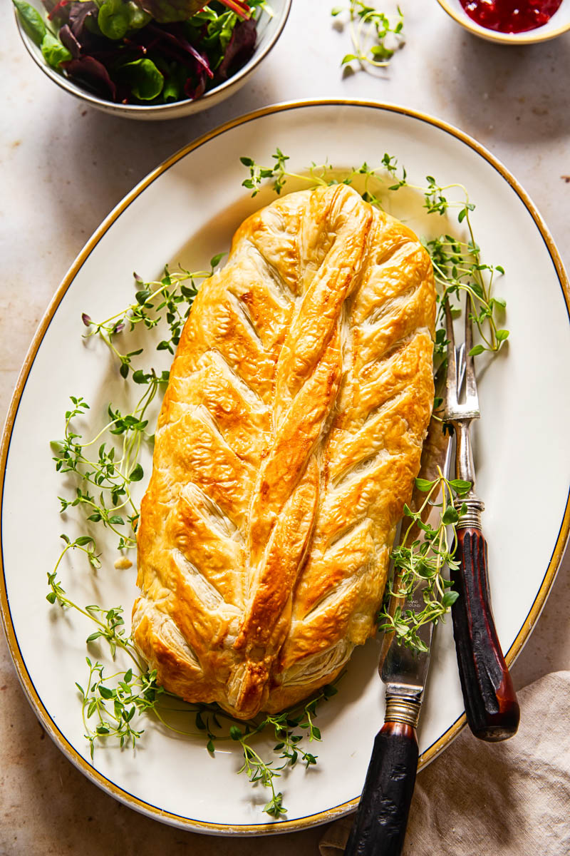 vegetarian Wellington on white platter, salad in bowl, cranberry sauce