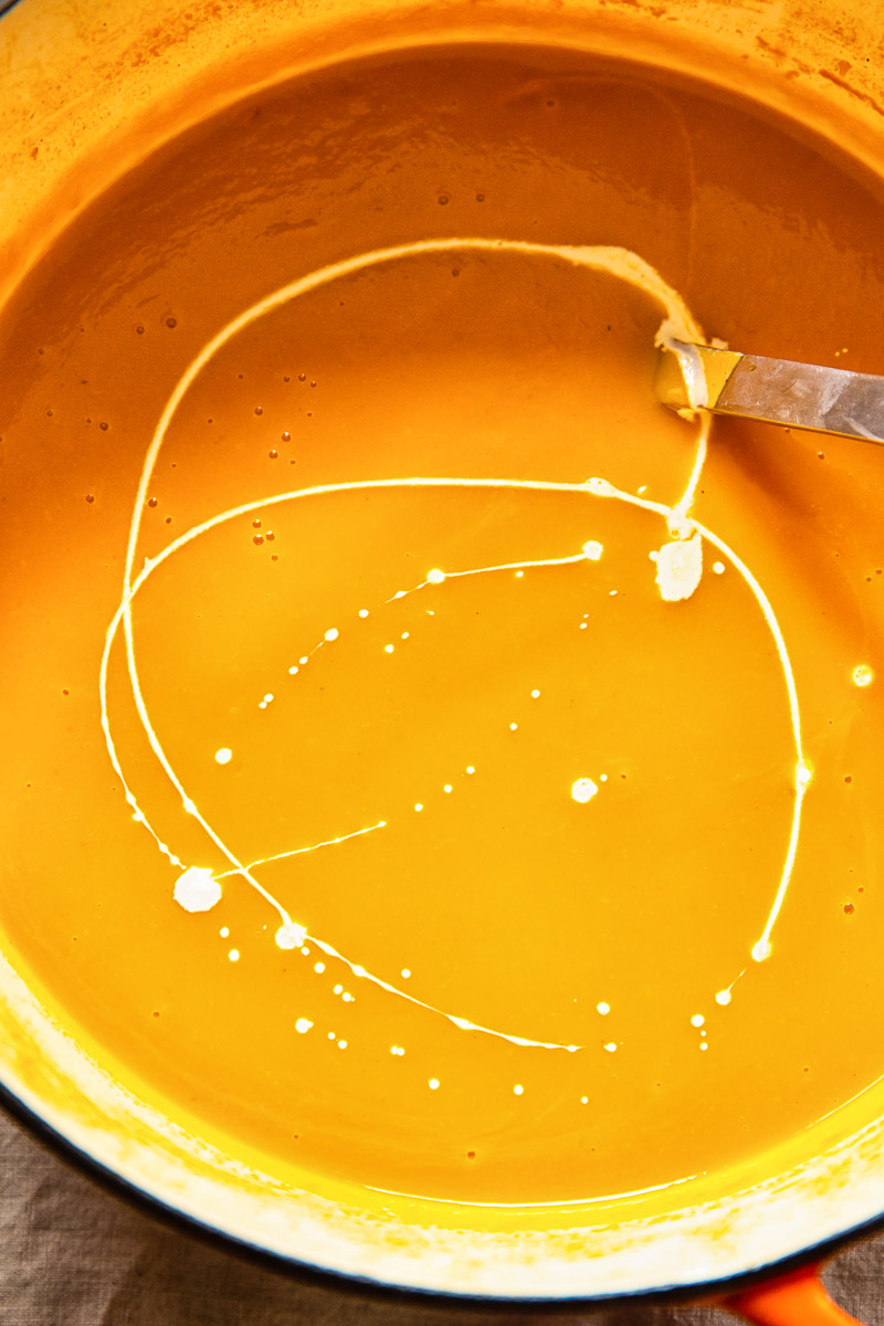 squash soup in a pot with a cream swirl