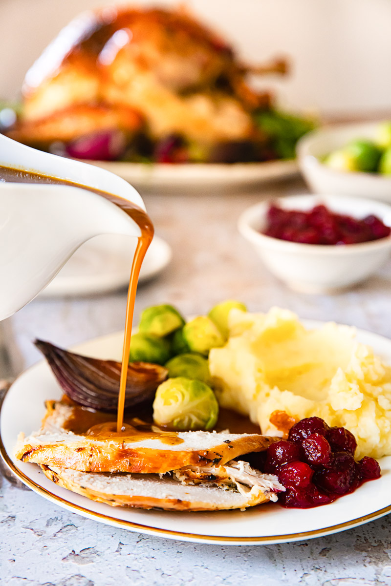 gravy being poured on sliced of turkey