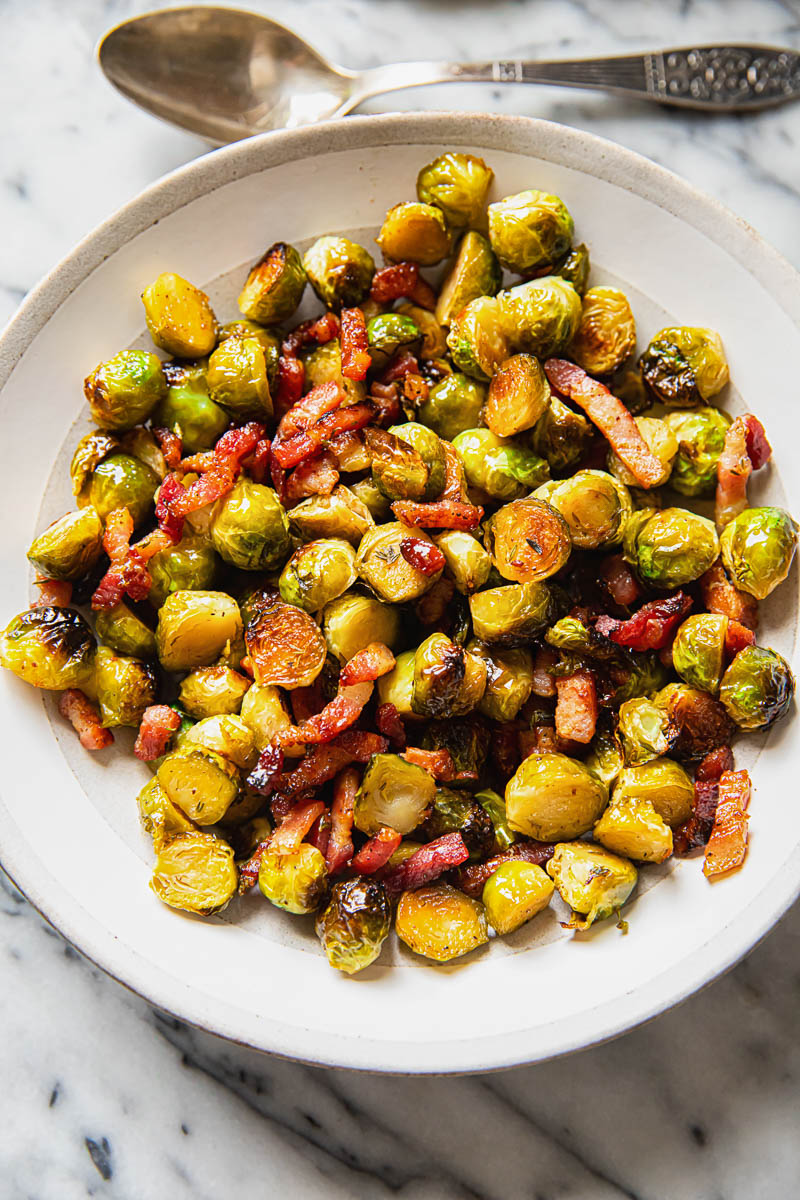 Brussels sprouts with bacon in a cream bowl on marble background