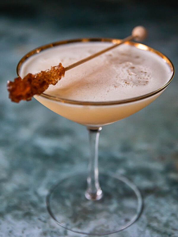 whisky sour in cocktail glass with brown sugar stir stick resting on top