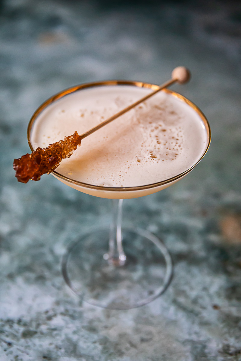 top down view of maple cider whiskey sour on dark blue background