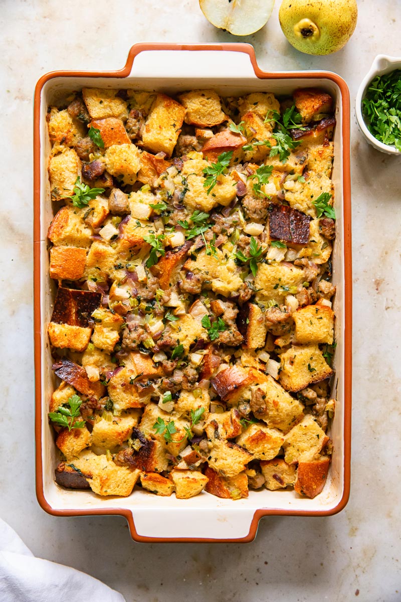 sausage stuffing in a rectangular pan, cut pear and herbs in a round dish
