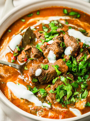 beef goulash with sour cream and parsley in cream coloured pot