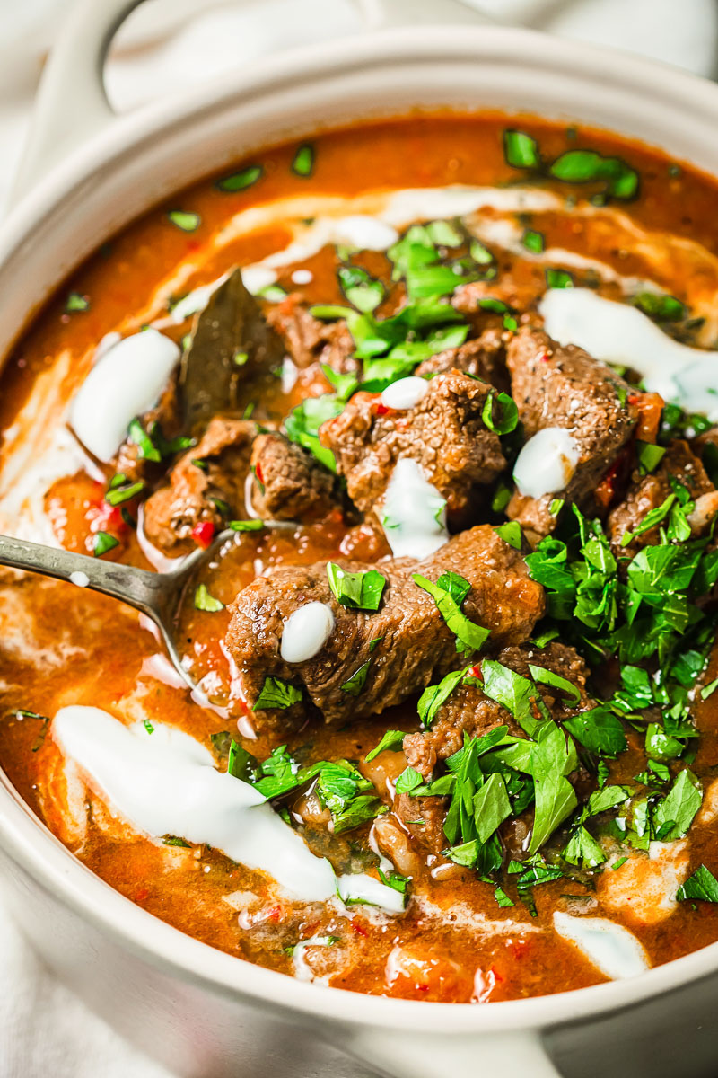 beef goulash with sour cream and parsley in cream coloured pot