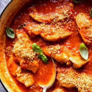 chicken in tomato sauce topped with fresh basil and breadcrumbs