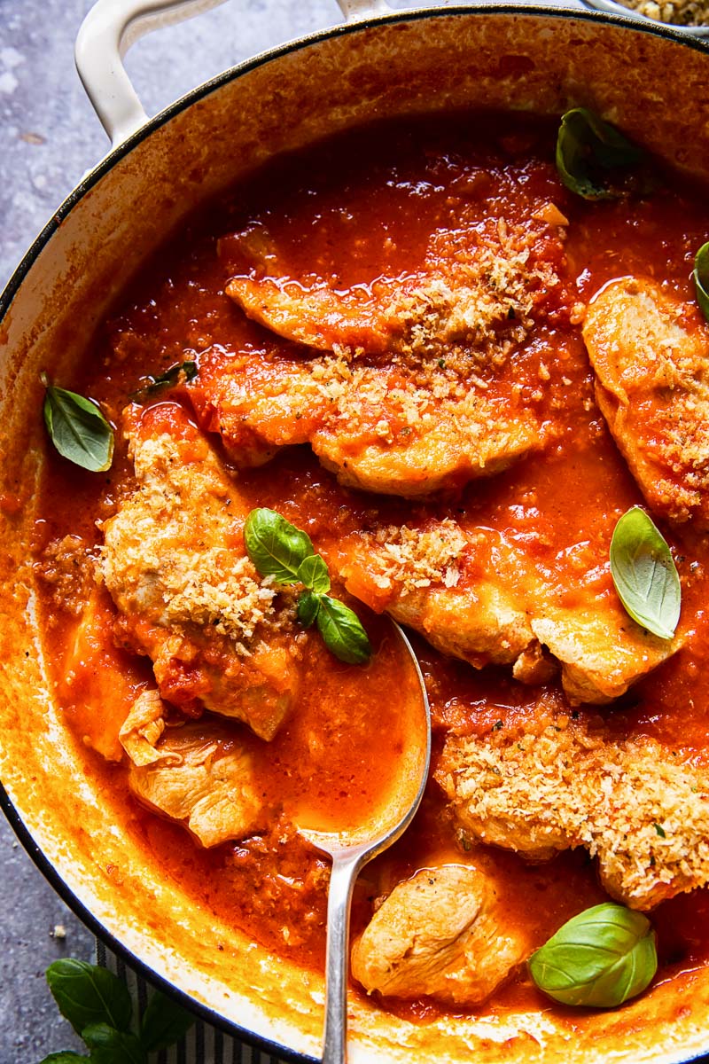 chicken in tomato sauce topped with fresh basil and breadcrumbs