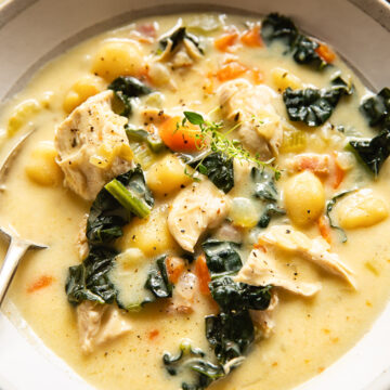 chicken gnocchi soup in a cream coloured bowl with a spoon in it