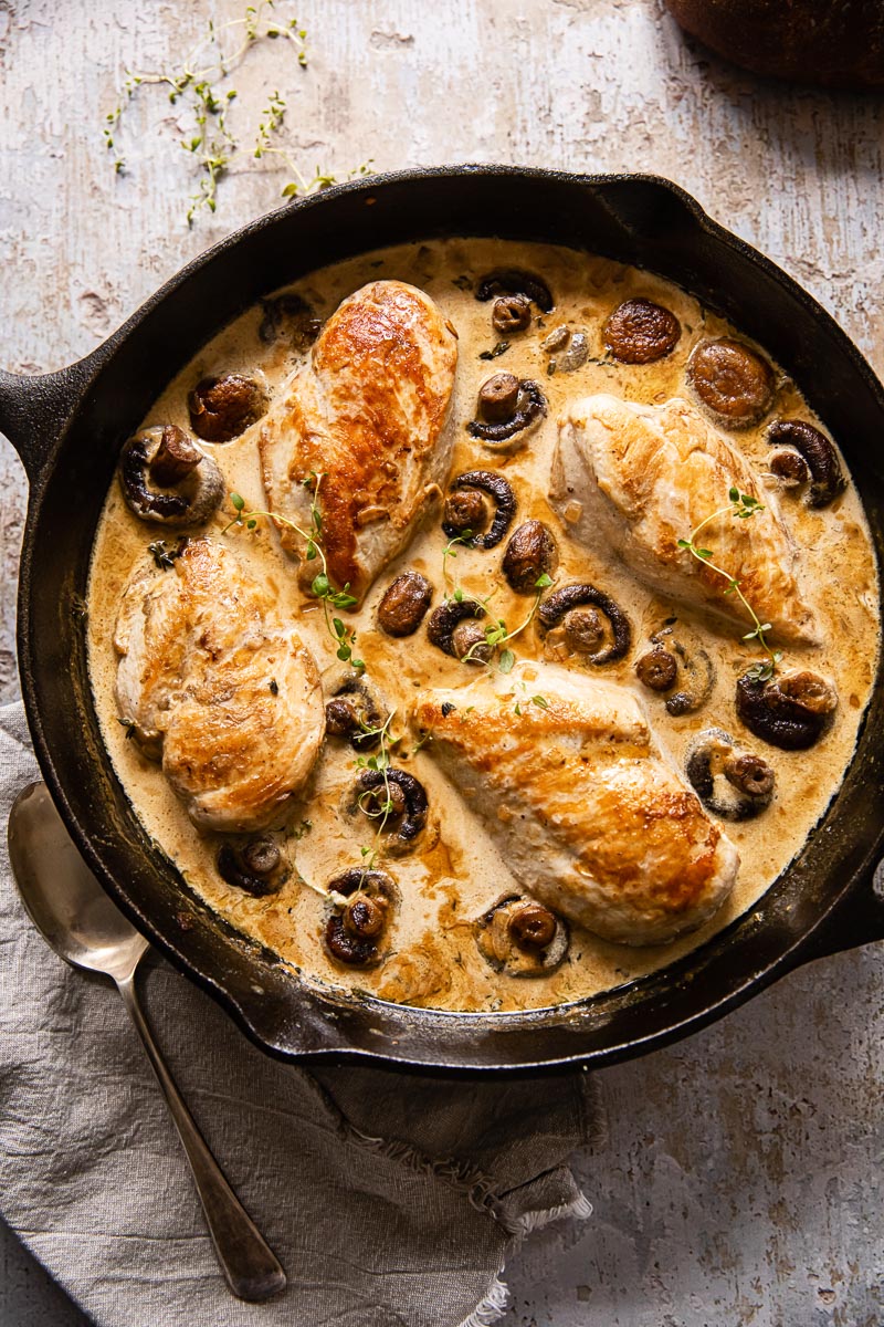 top down view of chicken supreme with mushrooms in cream sauce in cast iron skillet 