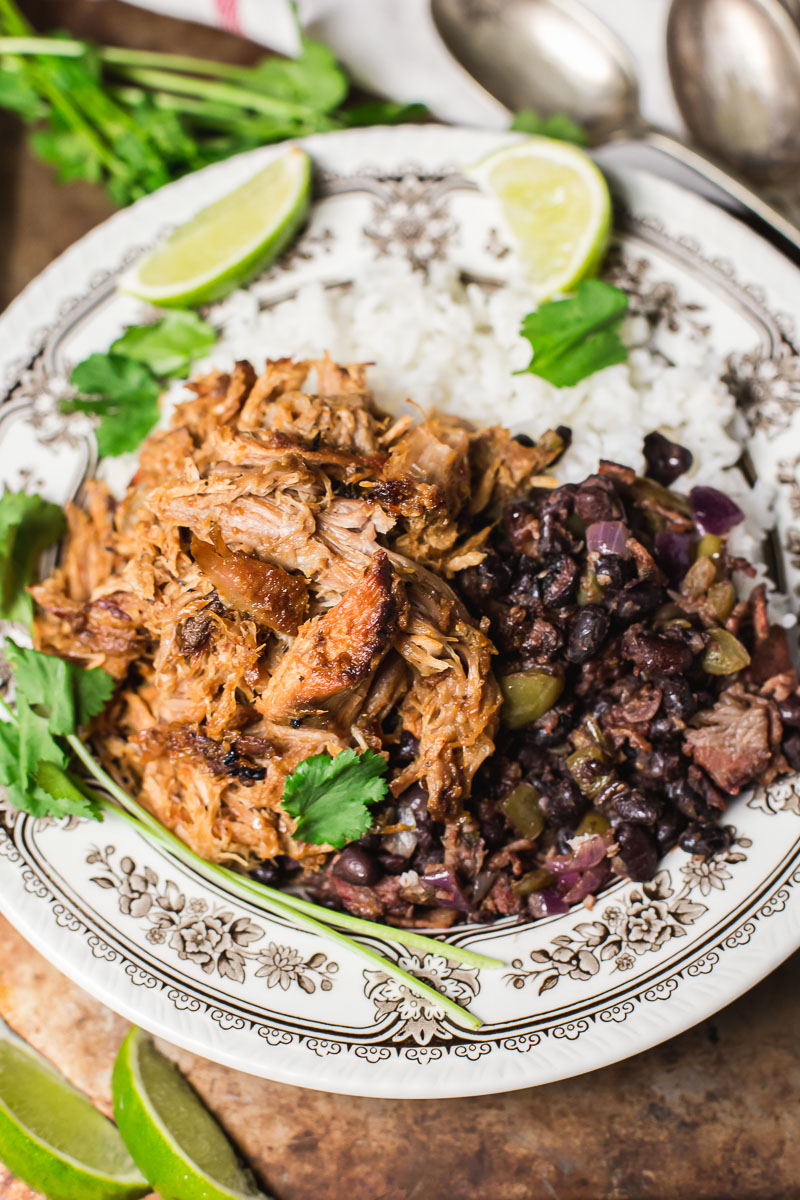 Cuban style pork and black bean on top of white rice, two slices of lime.