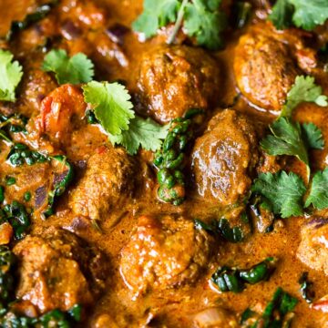 meatballs in sauce topped with cilantro leaves