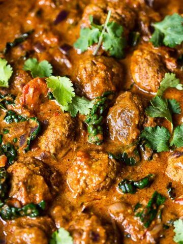 meatballs in sauce topped with cilantro leaves
