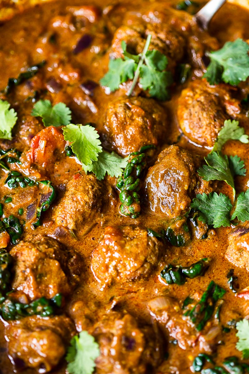 meatballs in sauce topped with cilantro leaves