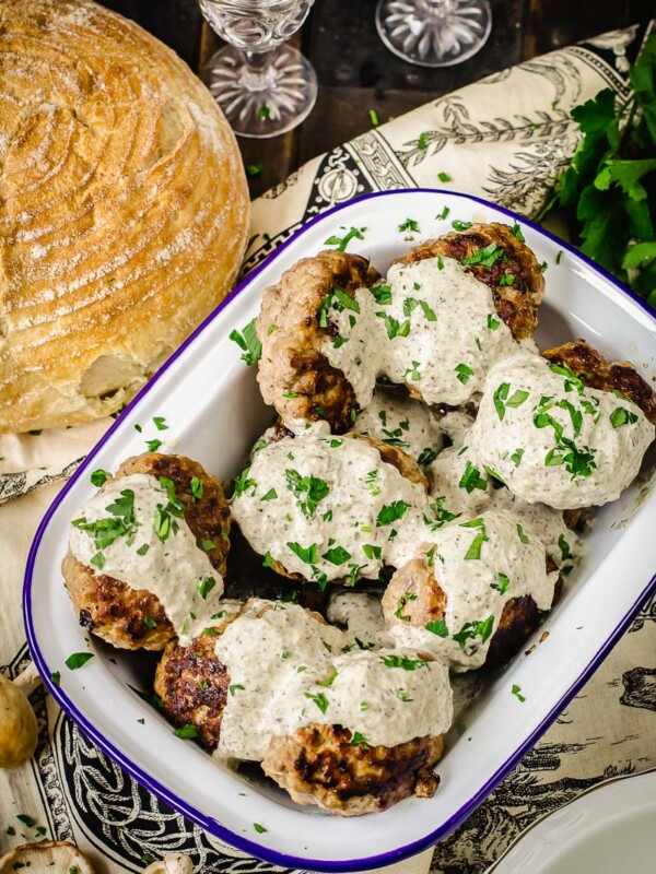 meat patties with mushroom sauce poured over them and sprinkled with fresh herbs