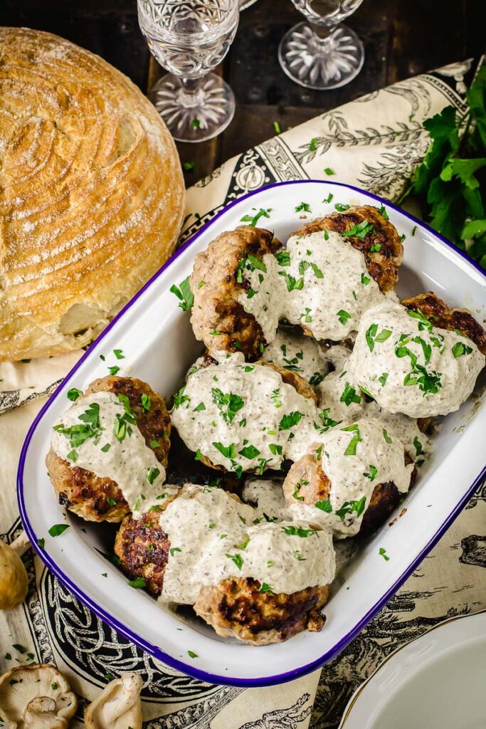 meat patties with mushroom sauce poured over them and sprinkled with fresh herbs