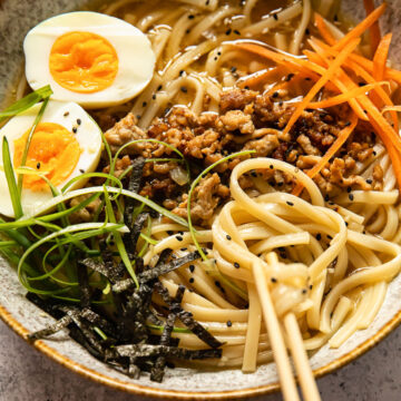 udon noodle soup topped with ground pork, boiled egg, green onion and carrots