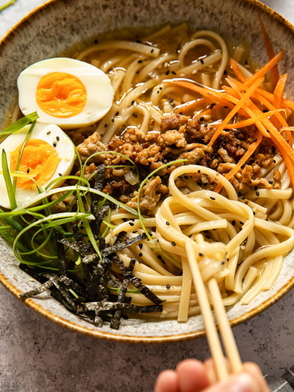 udon noodle soup topped with ground pork, boiled egg, green onion and carrots