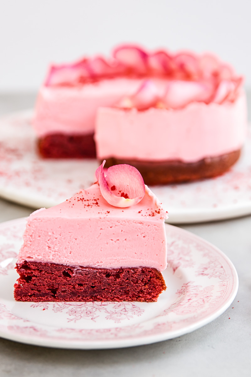 a slice of red velvet cake topped with pink white chocolate truffle layer
