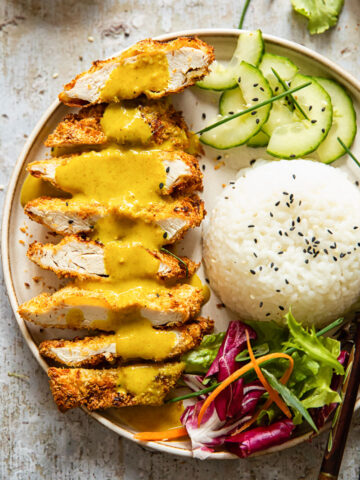 chicken katsu with curry poured over, rice, sliced cucumber