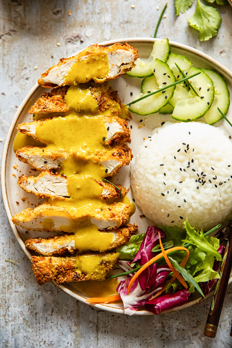 chicken katsu with curry poured over, rice, sliced cucumber