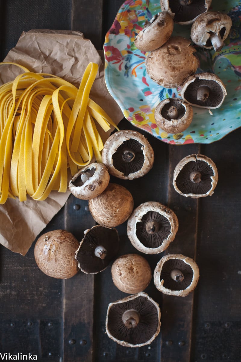 fresh tagliatelle and portobello mushrooms on dark background