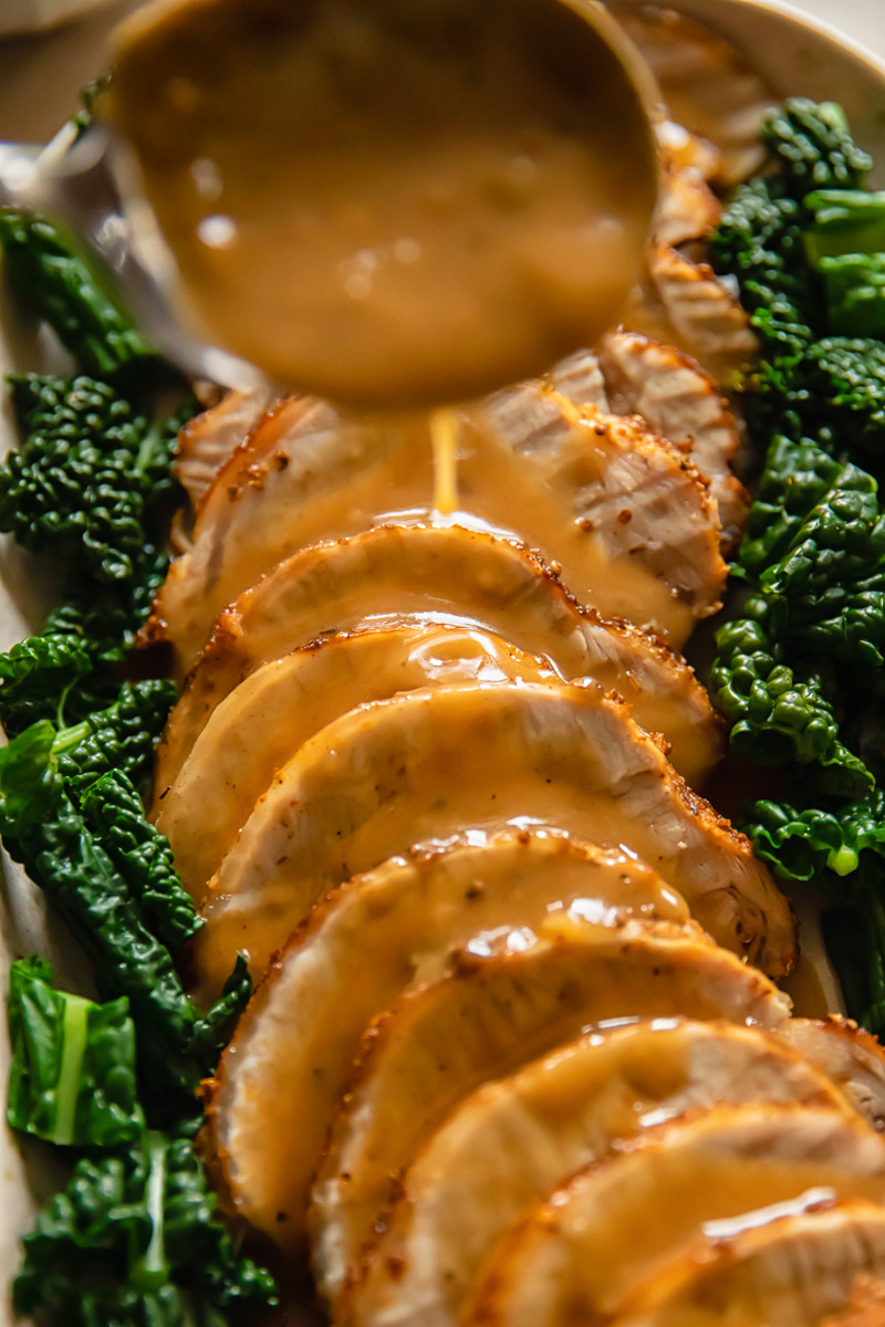 sliced pork loin roast with gravy being poured over it