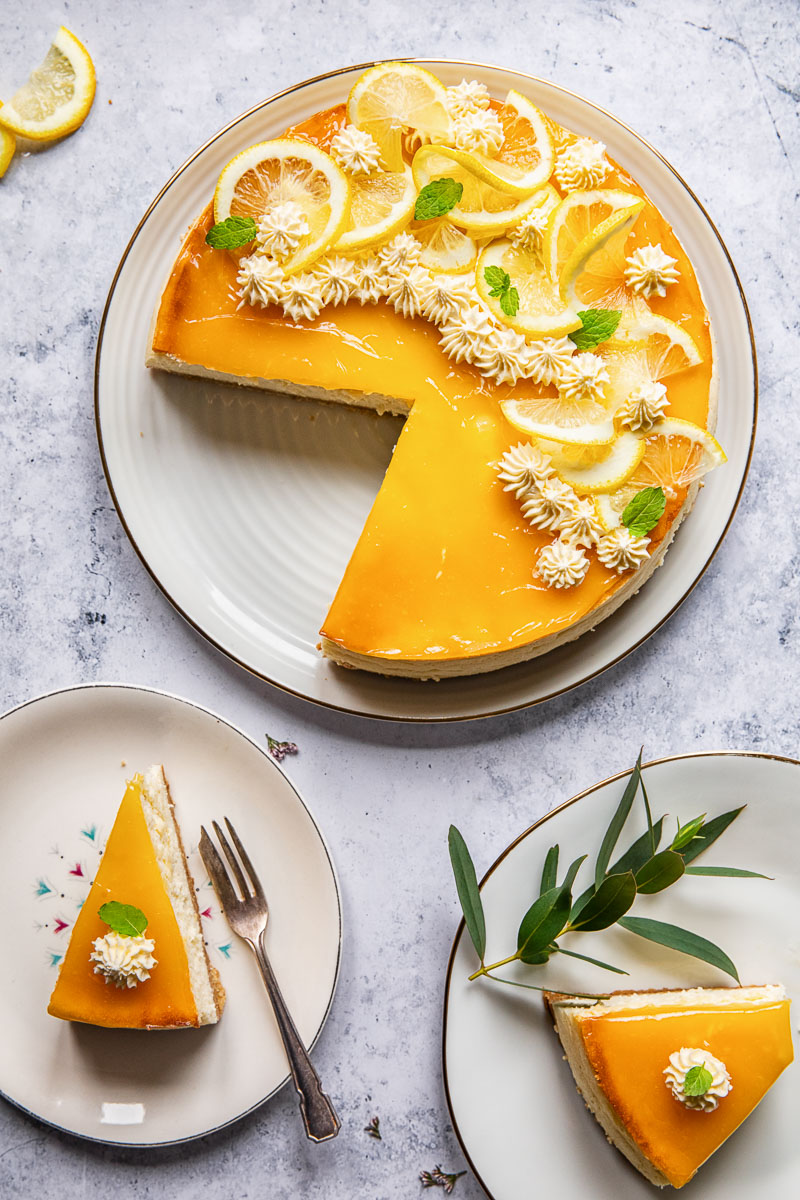 top down view of lemon cheesecake with two slices cut out of it and placed on plates