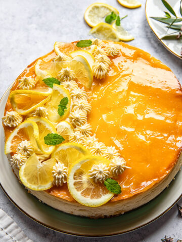 lemon cheesecake decorated with lemon slices and whipped cream rosettes