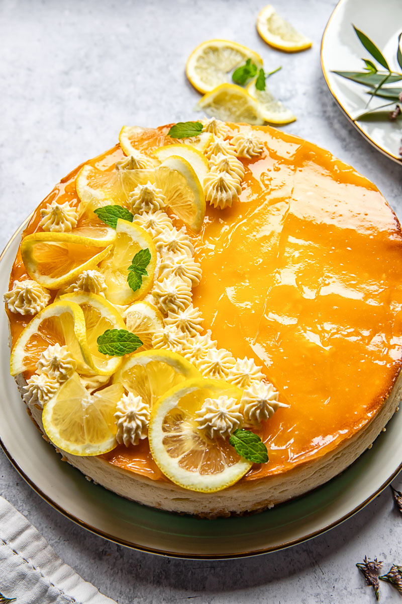 lemon cheesecake decorated with lemon slices and whipped cream rosettes