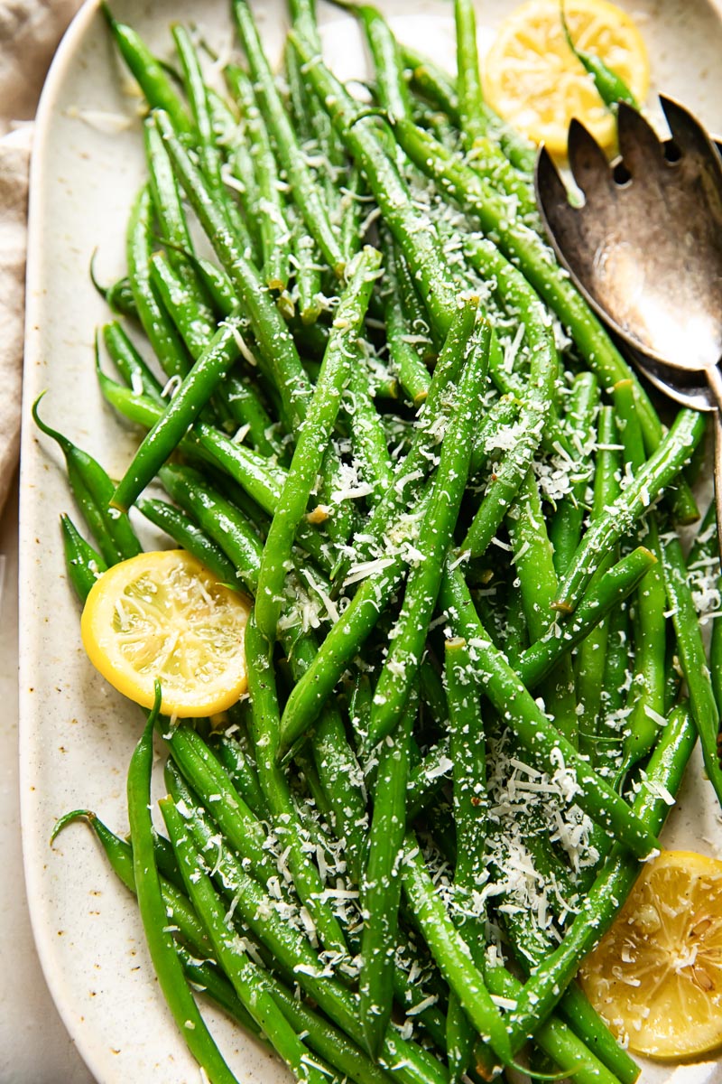 green beans topped with Parmesan and slices of lemon on a platter