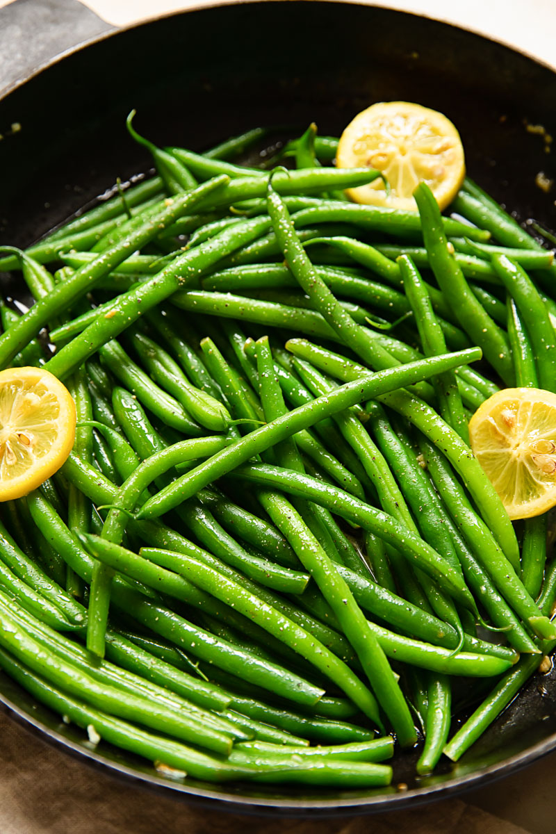 green beans with lemon slices in a cast iron pan