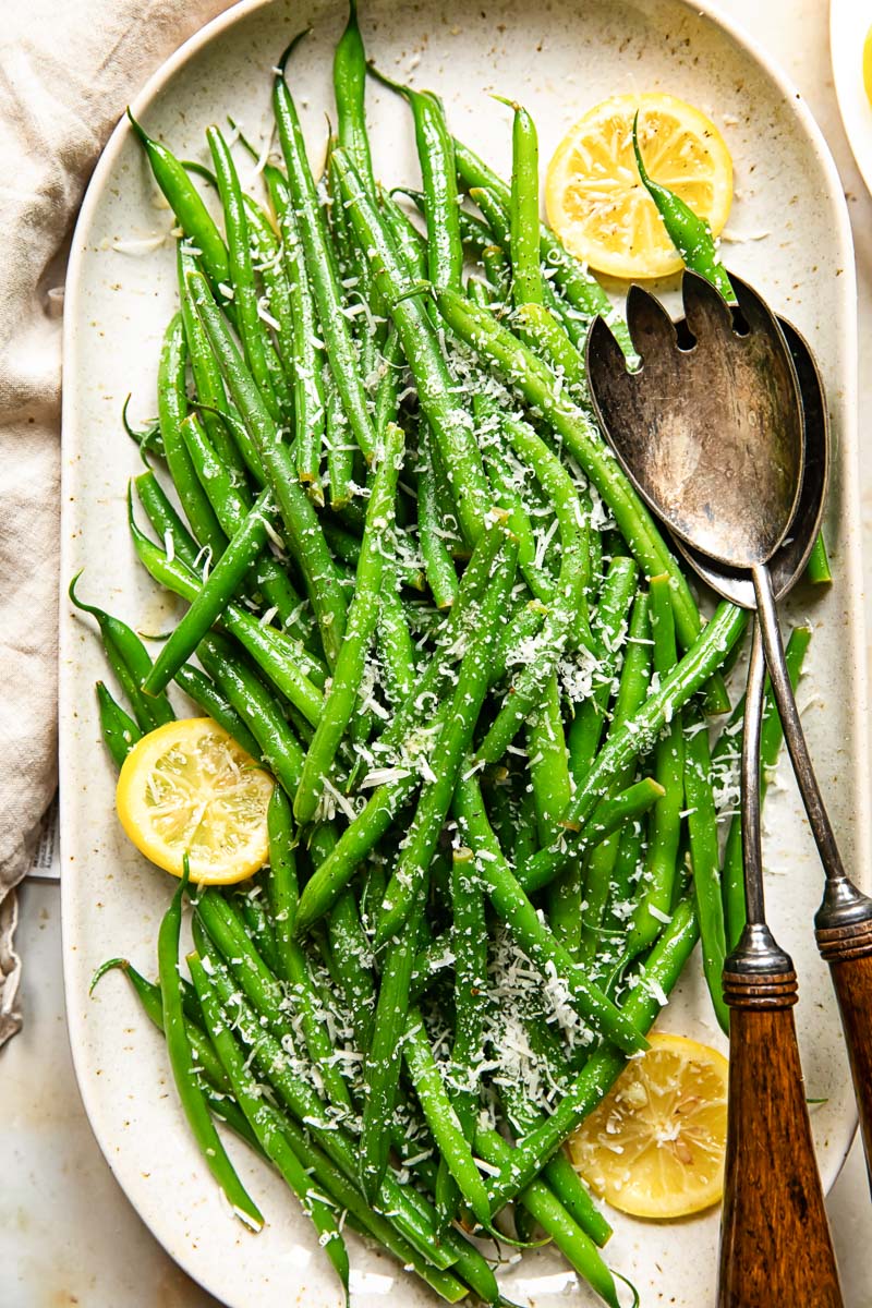 top down view of green beans with lemon slices and Parmesan