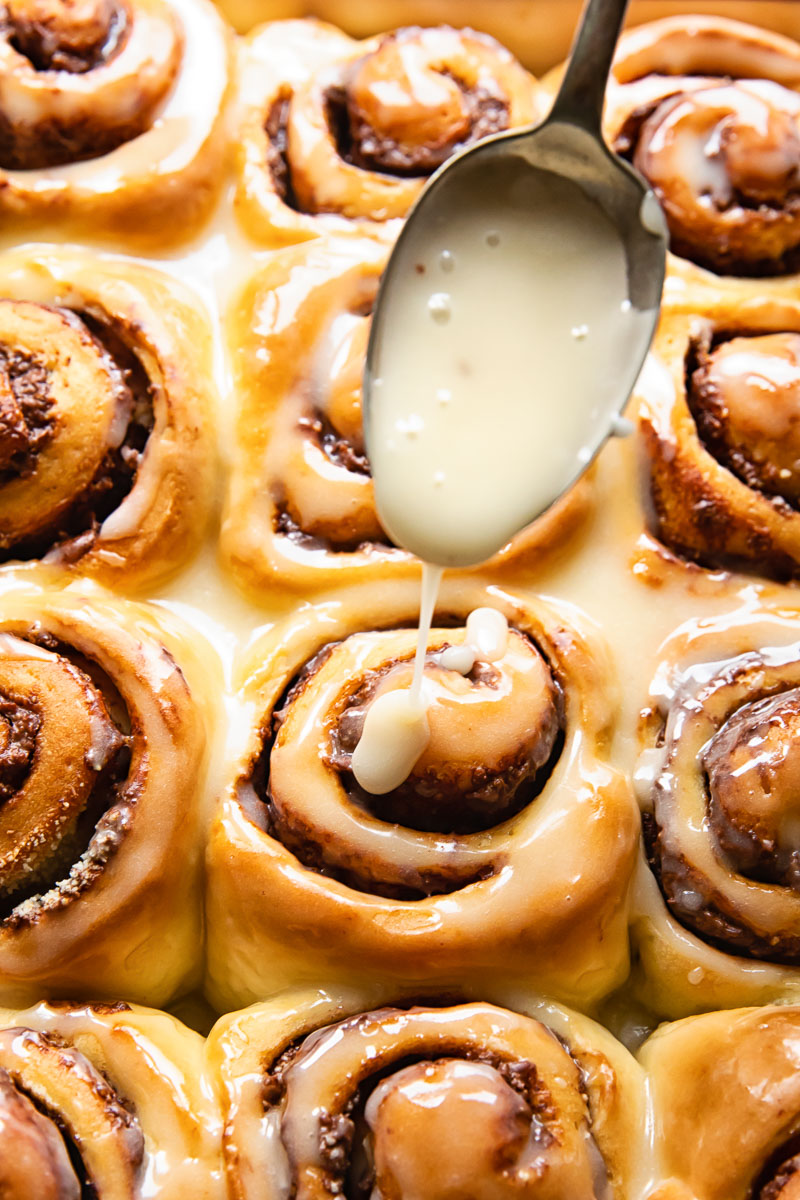 chocolate rolls being glazed with sugar icing