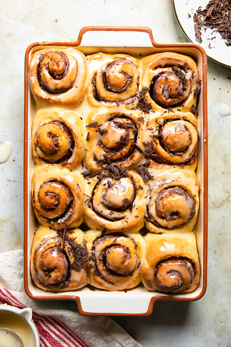 top down view of chocolate rolls topped with a sugar glaze and chopped chocolate