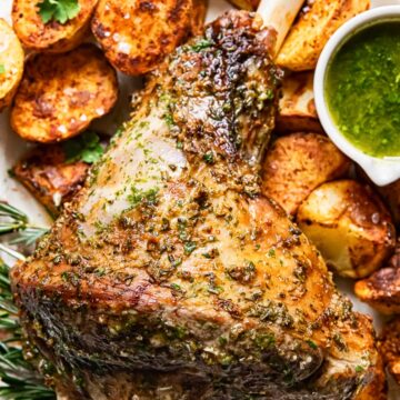 top down view of roast leg of lamb, mint sauce and roast potatoes