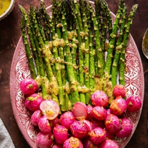 top down view on roasted asparagus and radishes with vinaigrette drizzled over.