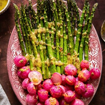 top down view on roasted asparagus and radishes with vinaigrette drizzled over.
