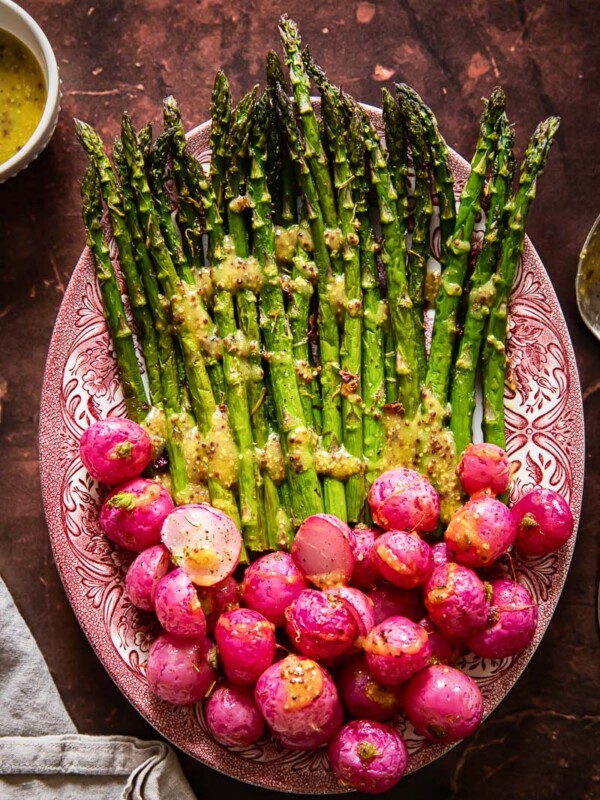 top down view on roasted asparagus and radishes with vinaigrette drizzled over.